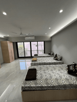 Shared PG room with three beds and a balcony window